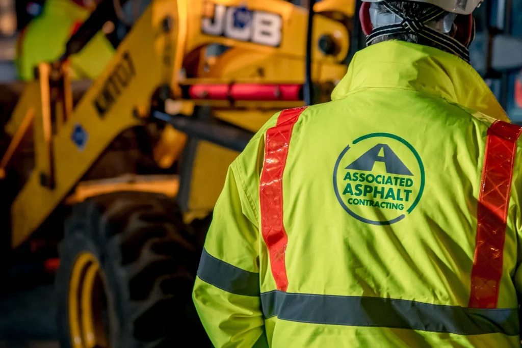 Close up of AA employee in branded PPE with digger in the back ground